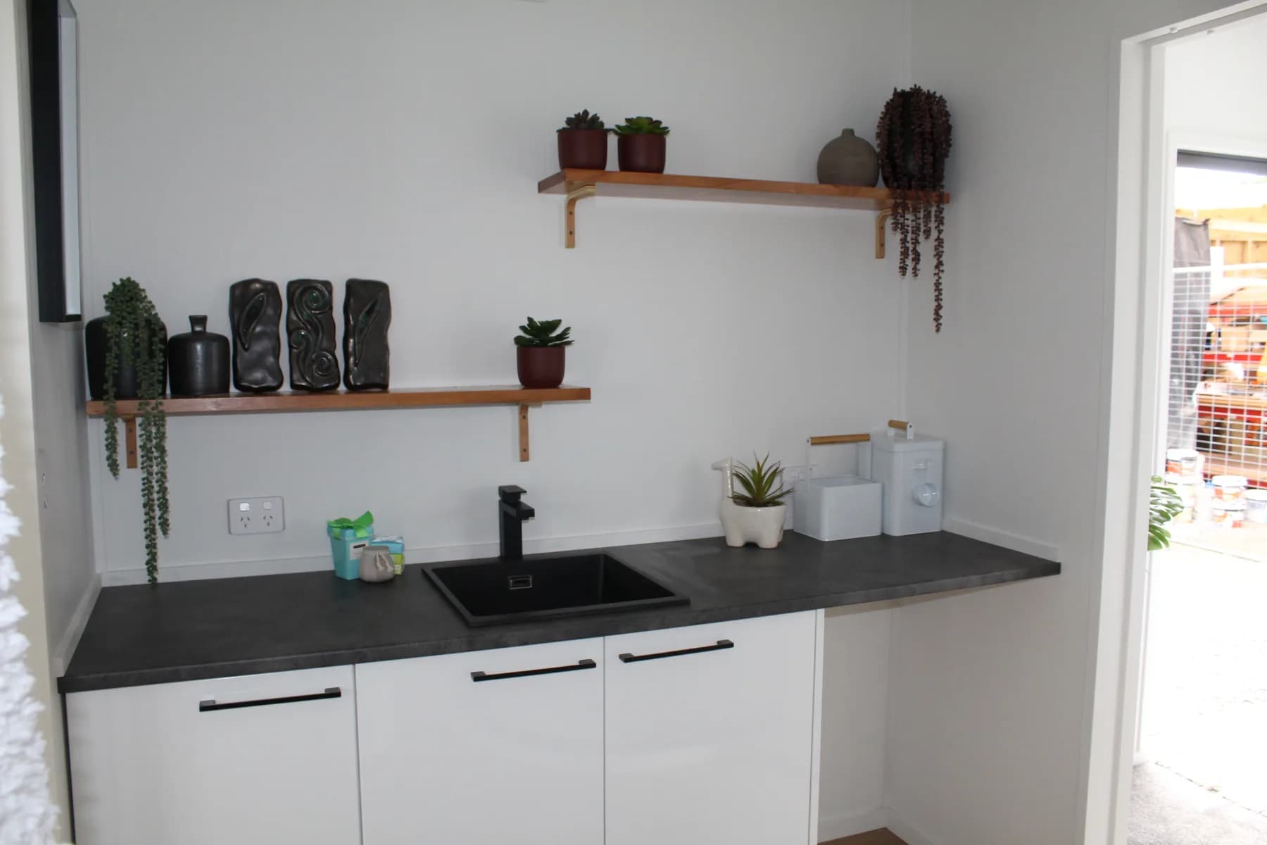 Kitchen bench with open timber shelving and a dark benchtop