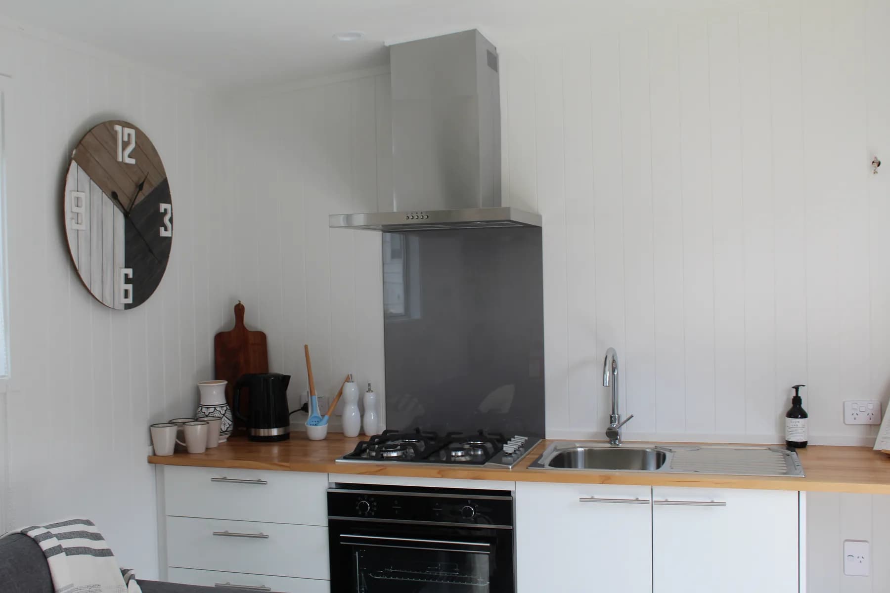 Kitchen with gas hob, electric oven, ducted rangehood and round mirror