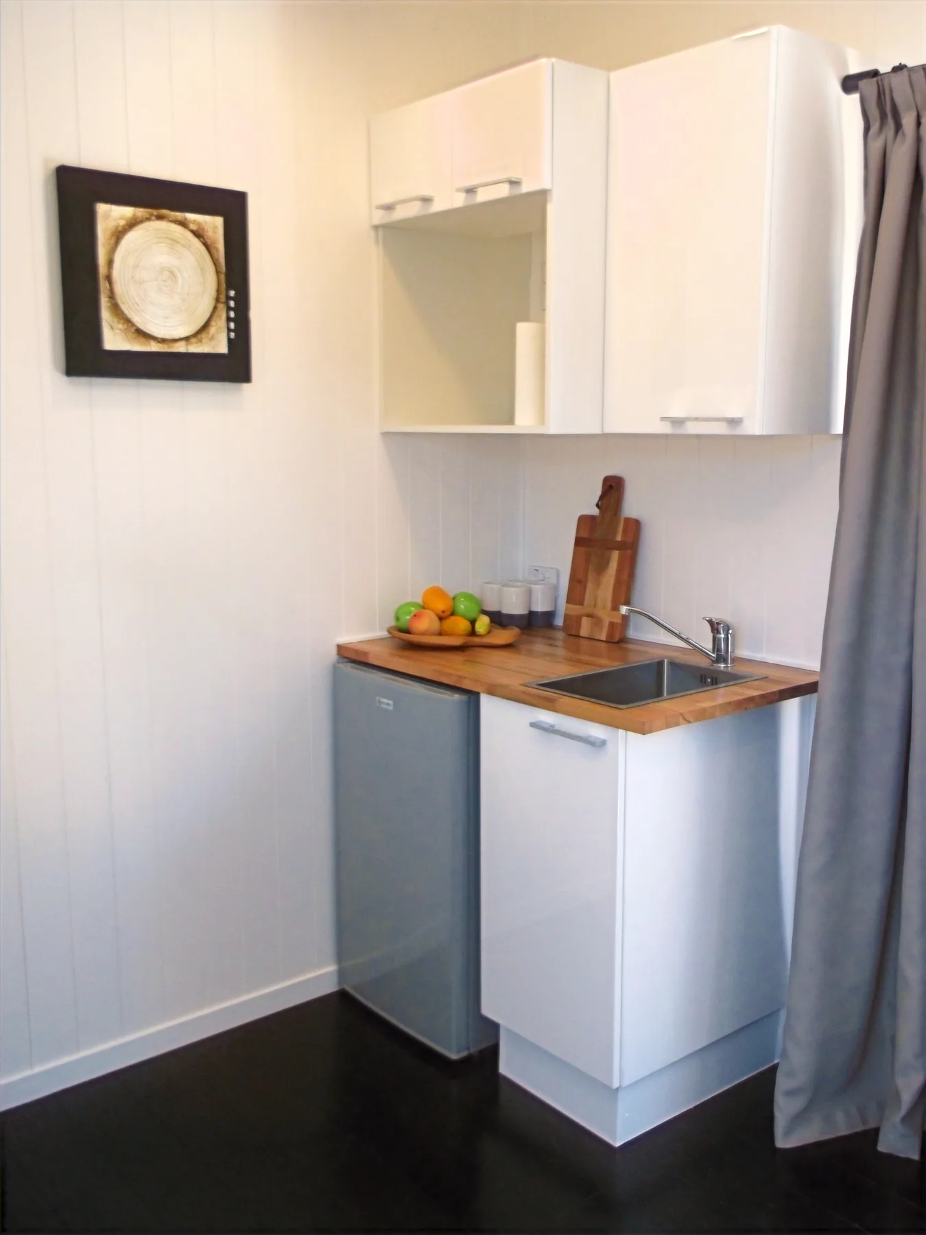 Compact kitchenette with timber benchtop and white base units