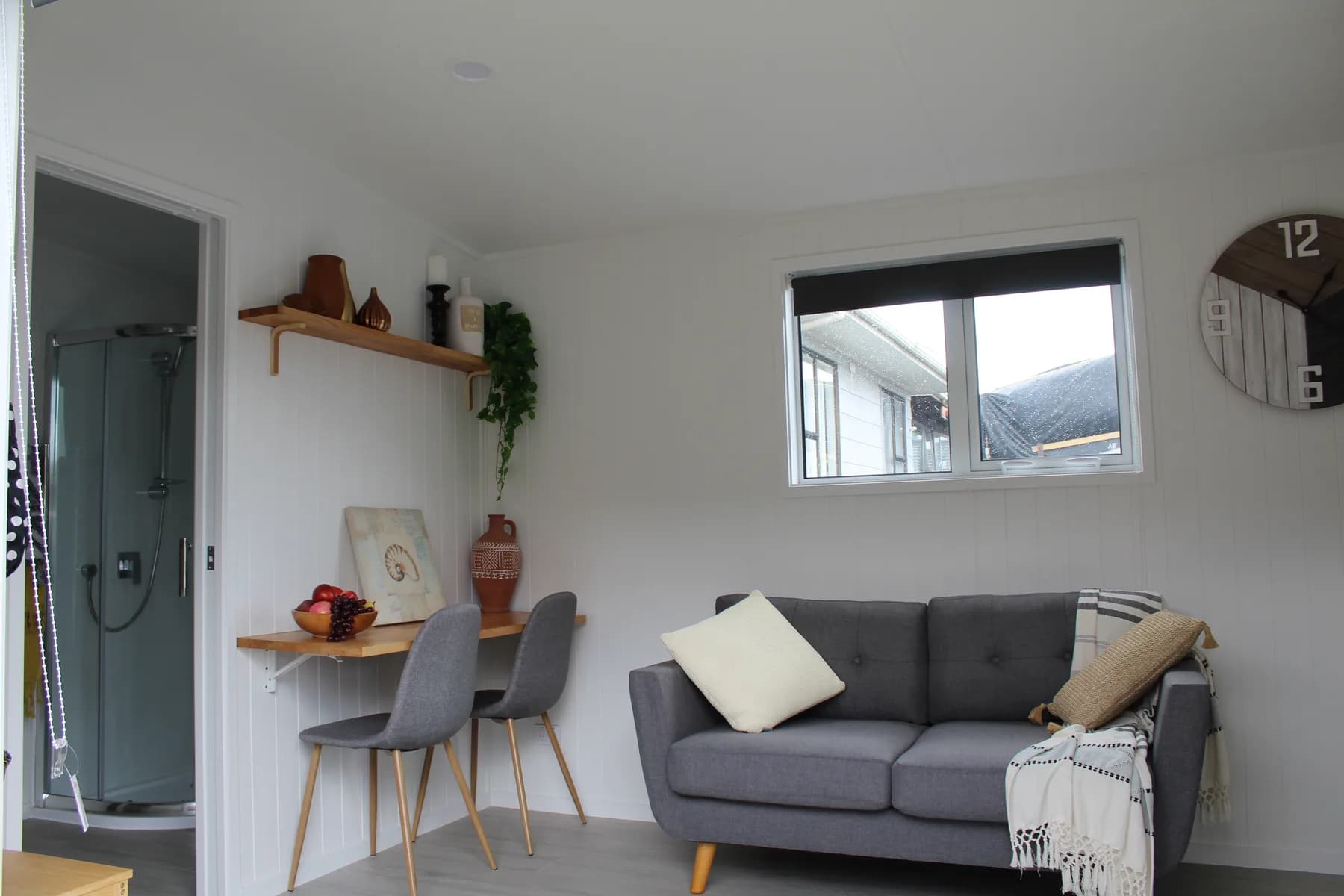Living area of a completed KDL tiny home with sofa, dining table and timber shelving