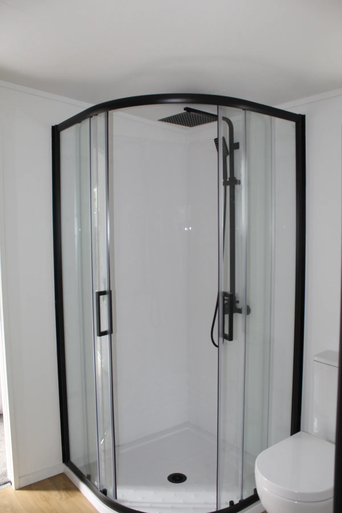Installed shower unit with glass door and white surround